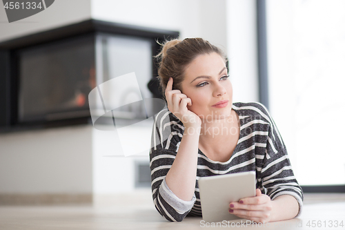 Image of woman using tablet computer in front of fireplace