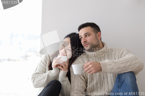 Image of multiethnic couple enjoying morning coffee by the window