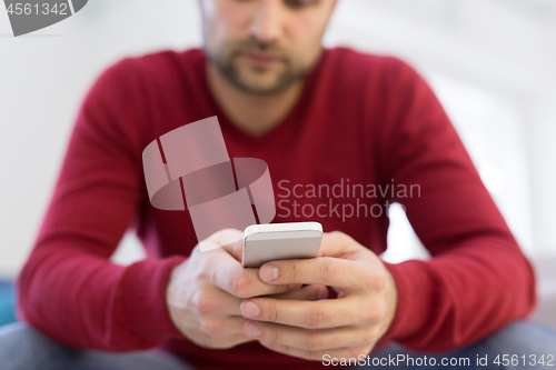 Image of young man using a mobile phone  at home