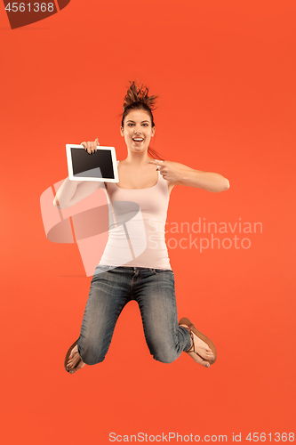 Image of Image of young woman over blue background using laptop computer or tablet gadget while jumping.