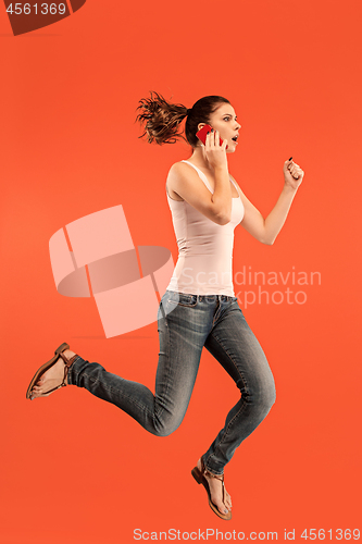 Image of Full length of pretty young woman with mobile phone while jumping