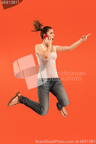 Image of Full length of pretty young woman with mobile phone while jumping