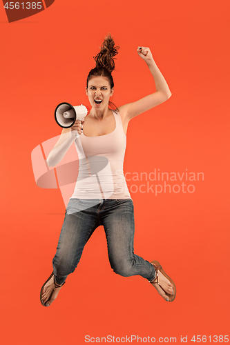 Image of Beautiful young woman jumping with megaphone isolated over red background