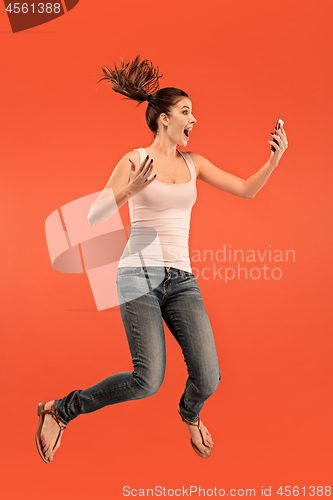 Image of Full length of pretty young woman with mobile phone while jumping