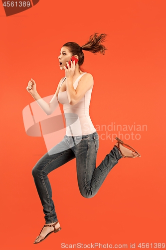 Image of Full length of pretty young woman with mobile phone while jumping