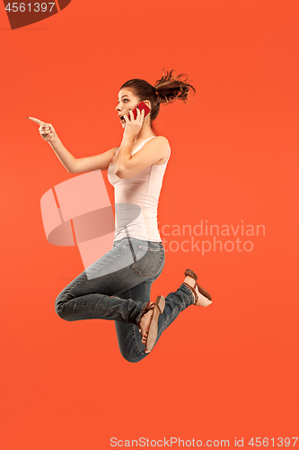 Image of Full length of pretty young woman with mobile phone while jumping