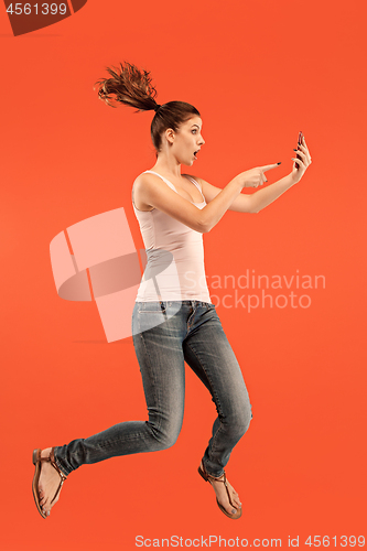 Image of Full length of pretty young woman with mobile phone while jumping