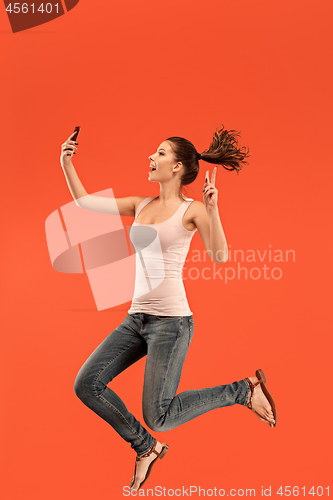 Image of Image of young woman over blue background using laptop computer or tablet gadget while jumping.