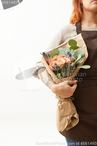 Image of Woman with red hair holds beautiful colourful blossoming flower bouquet of fresh roses living coral color on a white background. Copy space. Mother\'s Day.
