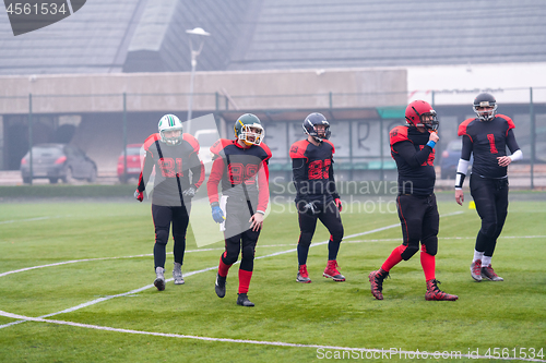 Image of confident American football players leaving the field