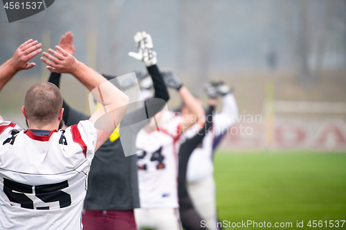 Image of american football players stretching and warming up