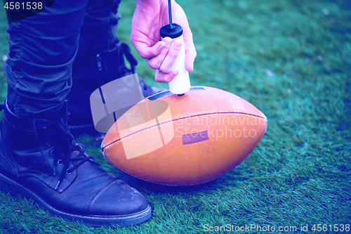 Image of man pumping air into american football ball