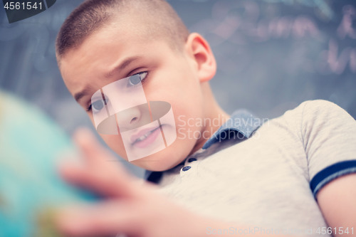 Image of boy using globe of earth in front of chalkboard