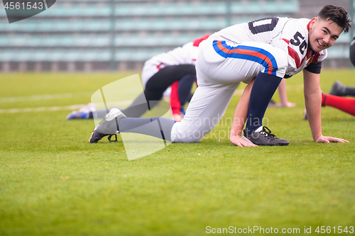 Image of american football players stretching and warming up