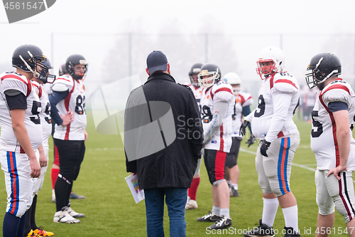 Image of american football players discussing strategy with coach