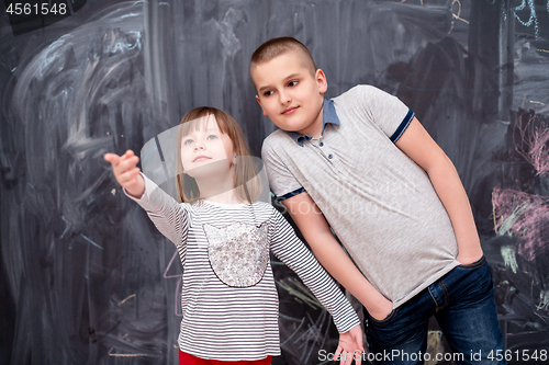 Image of boy and little girl standing in front of chalkboard