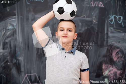 Image of happy boy holding a soccer ball on his head