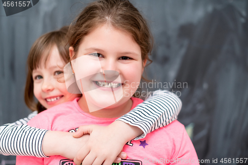 Image of little girls hugging in front of chalkboard