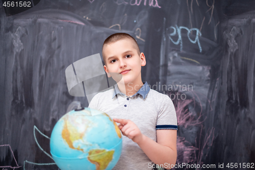 Image of boy using globe of earth in front of chalkboard