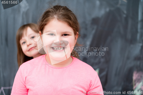 Image of little girls having fun in front of chalkboard