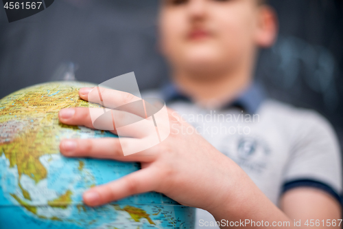 Image of boy using globe of earth in front of chalkboard