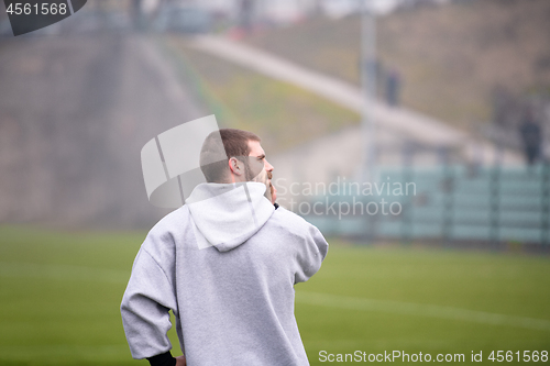 Image of american football player warming up and stretching