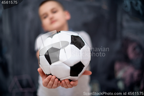 Image of happy boy holding a soccer ball in front of chalkboard