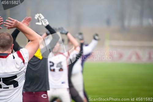 Image of american football players stretching and warming up