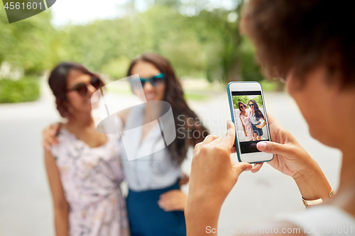Image of woman photographing her friends in summer park