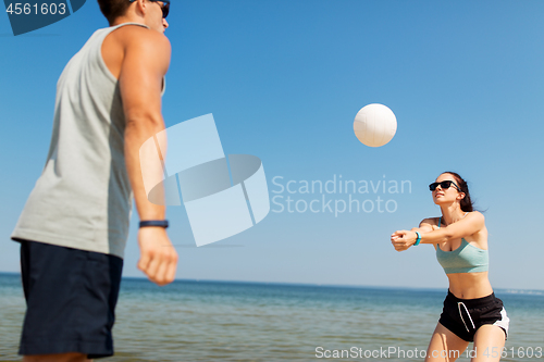 Image of happy couple playing volleyball on summer beach