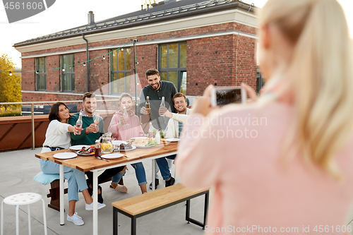 Image of happy friends photographing at rooftop party