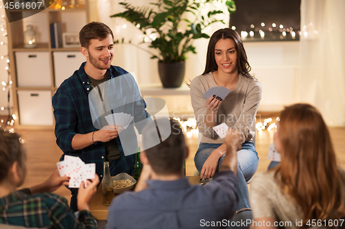 Image of friends playing cards game at home in evening