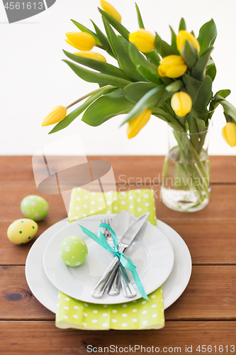 Image of easter egg, plates, cutlery and tulip flowers