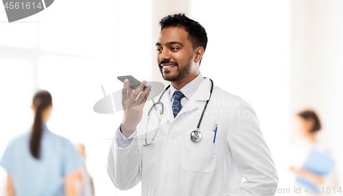 Image of smiling indian male doctor calling on smartphone