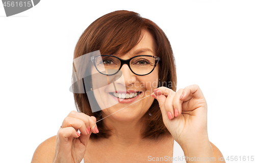 Image of senior woman cleaning her teeth by dental floss