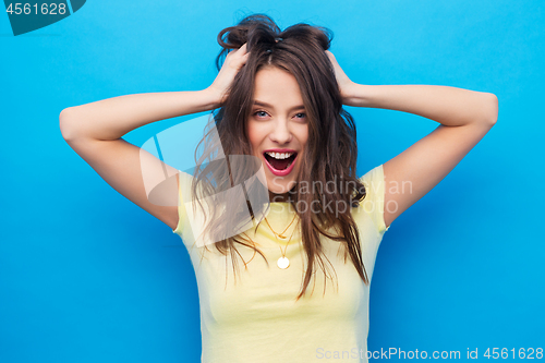 Image of smiling young woman holding to her head or hair