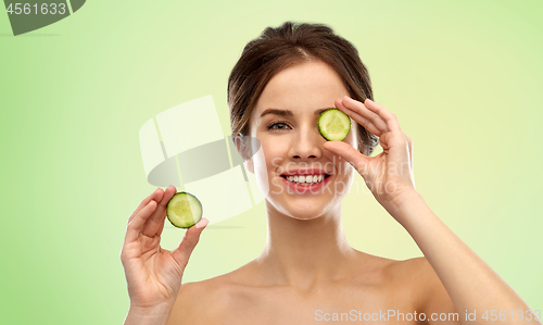 Image of smiling woman with cucumber over green background