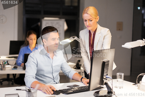 Image of business team with computer working late at office