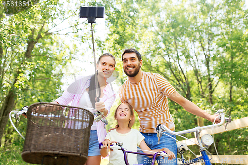 Image of happy family with bicycles taking selfie in summer