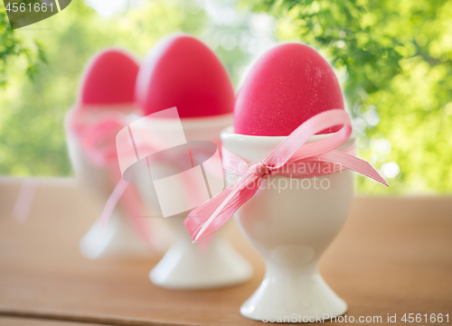 Image of pink colored easter eggs in holders on table