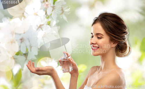 Image of happy woman with perfume over cherry blossoms