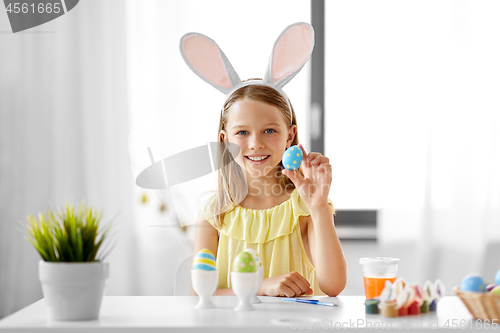 Image of happy girl coloring easter eggs at home