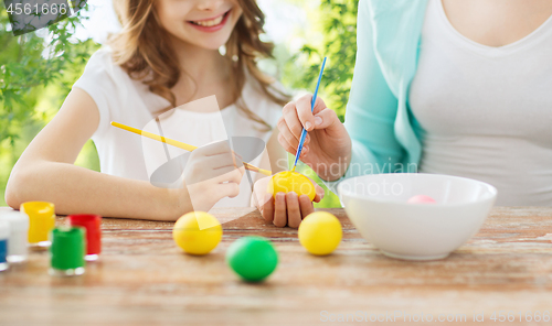 Image of happy smiling girl and mother coloring easter eggs