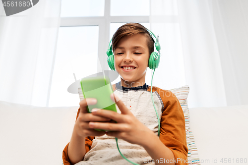 Image of happy boy with smartphone and headphones at home