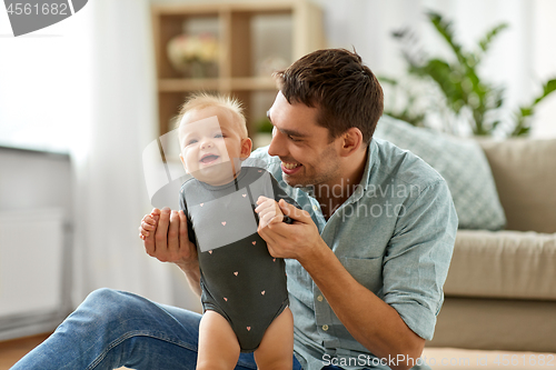 Image of happy father holding little baby daughter at home