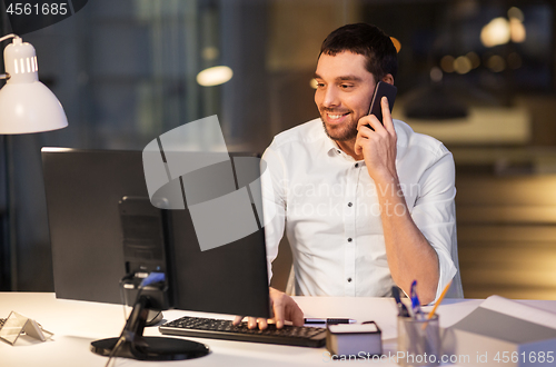 Image of businessman calling on smartphone at night office