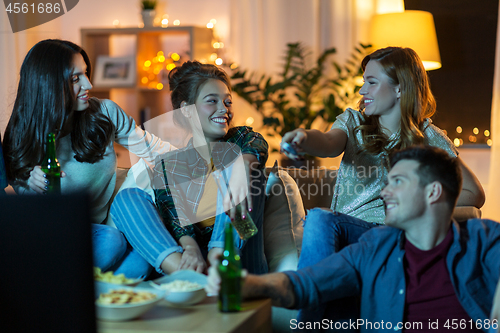 Image of friends with drinks and snacks watching tv at home