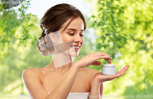 Image of happy young woman holding jar of cream