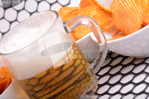 Image of Glass of light beer and potato chips on a abstract background