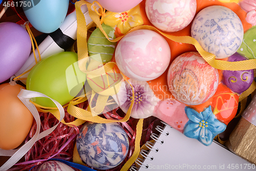 Image of Handcrafted easter eggs close up, white notepad, ribbons and decoration